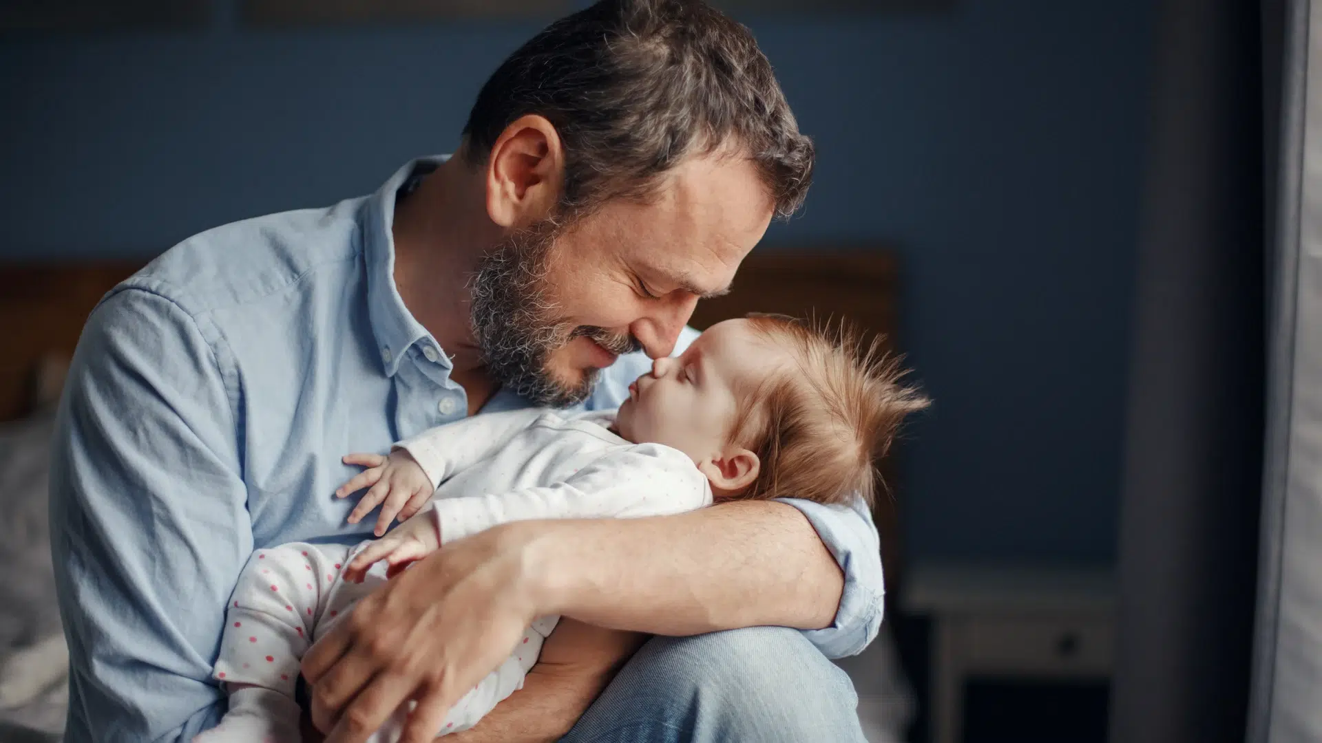 Homme avec barbe tenant un bébé endormi